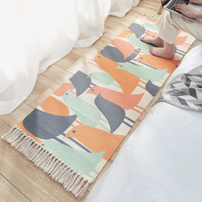 Colorful animal-patterned rug on a wooden floor with a person using a laptop.