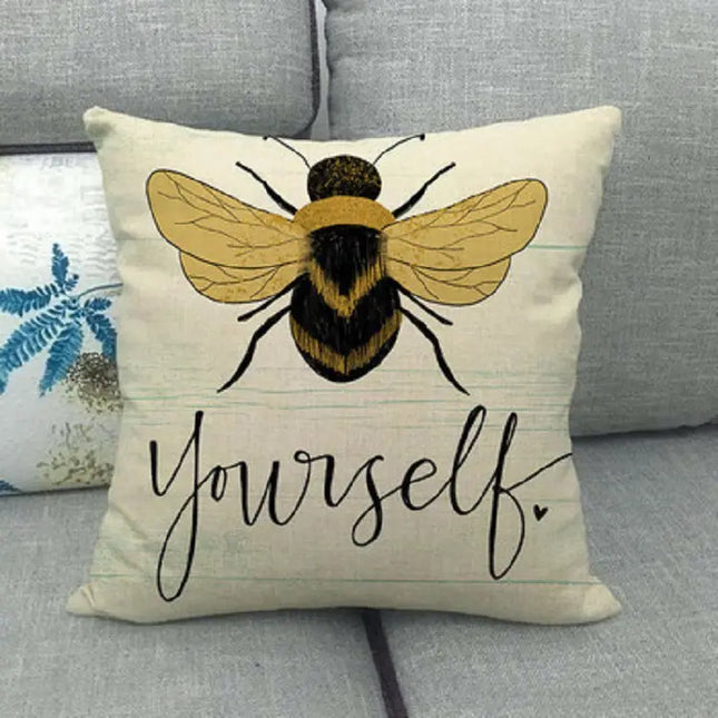 Pillow with a bee design and 'Be Yourself' text on a couch.