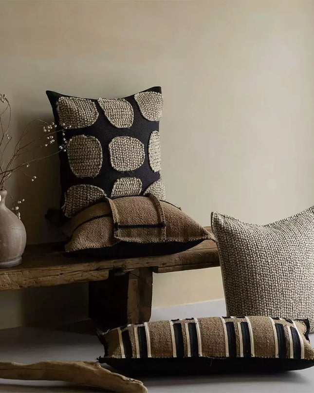 Decorative pillows on a wooden bench with a neutral background