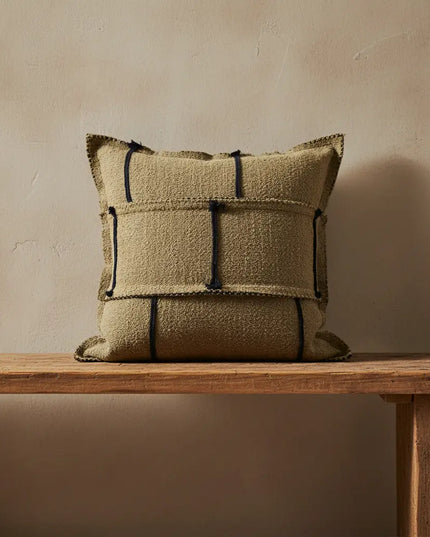 Textured pillow with geometric pattern on a wooden table against a beige wall