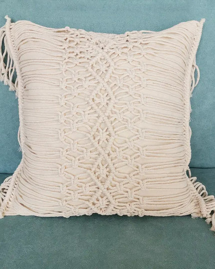 Beige macrame pillow with tassels on a teal background