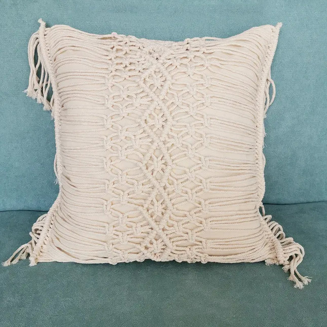 Beige macrame pillow with tassels on a teal background