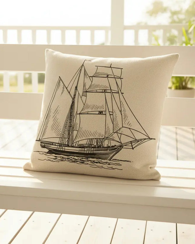 Decorative pillow with a sailboat design on a white bench outdoors.