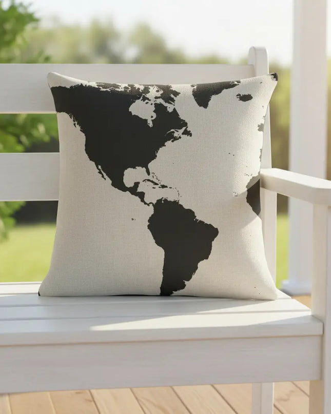 World map pillow on a white bench outdoors