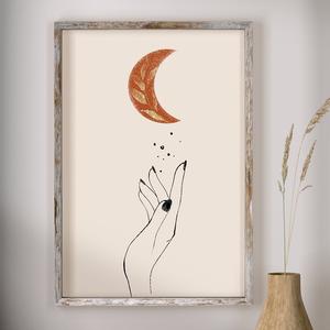 Decorative wall art with a hand holding a leaf and a moon, framed in a rustic style.