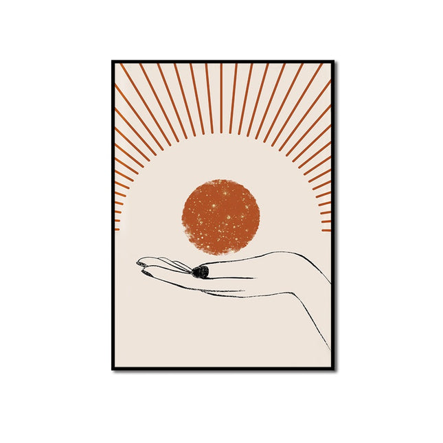 Framed artwork of a hand holding a small object with a sunburst design on a beige background