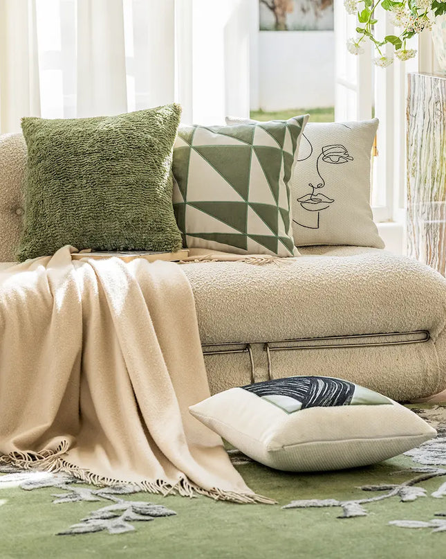 Beige sofa with decorative pillows and a blanket in a living room setting.
