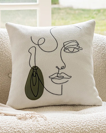 Decorative pillow with abstract face design on a beige couch