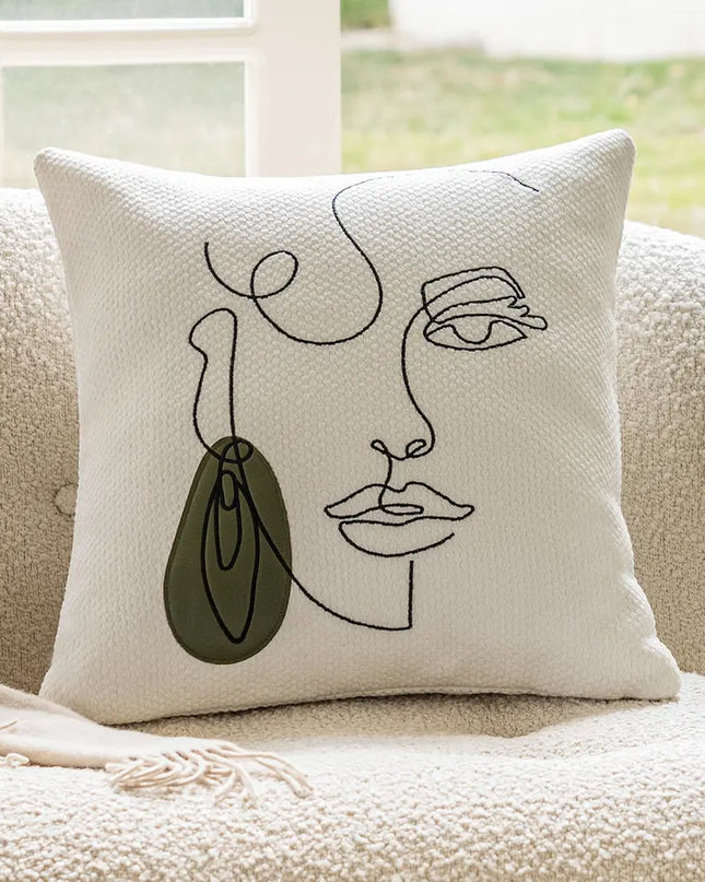 Decorative pillow with abstract face design on a beige couch