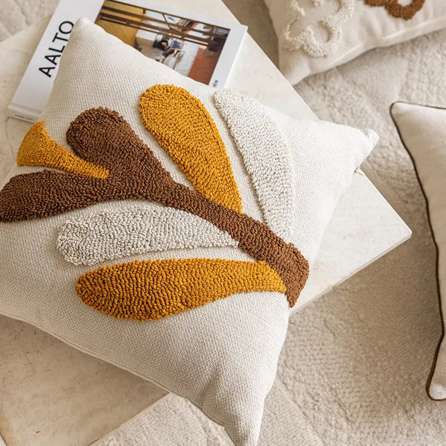 Decorative pillow with brown and yellow abstract design on a neutral background