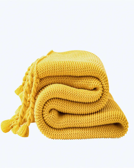 Yellow knitted blanket with tassels on a white background