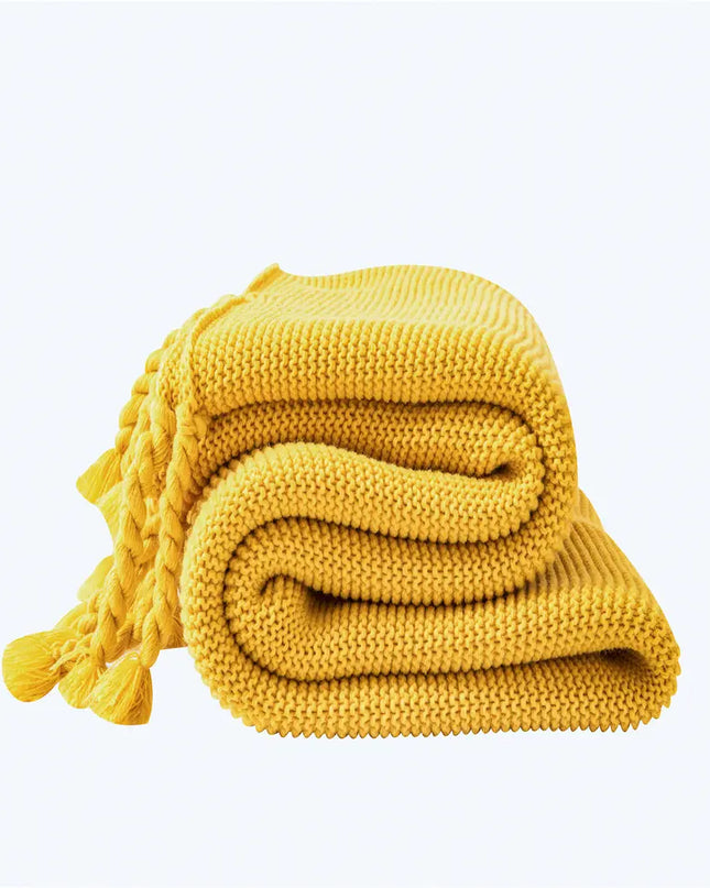 Yellow knitted blanket with tassels on a white background