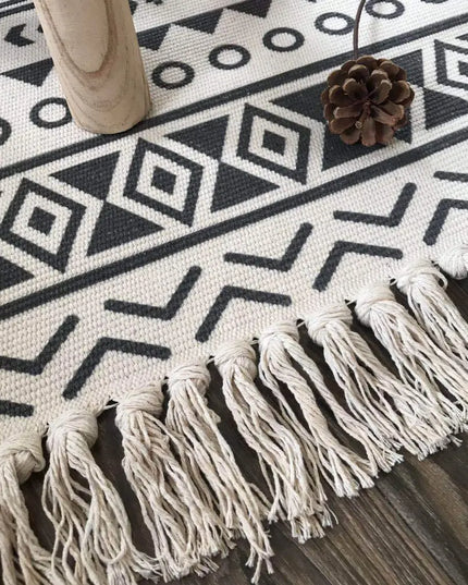 Black and white patterned rug with tassels on a wooden floor