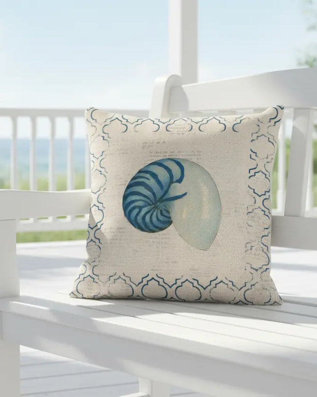 Decorative pillow with a shell design on a white bench on a porch.