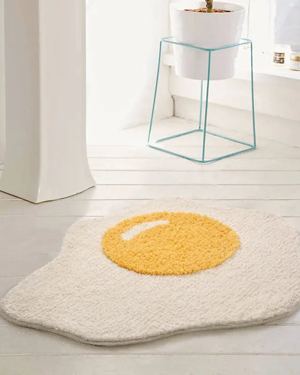 Poached edd design bath mat on a light wooden floor.