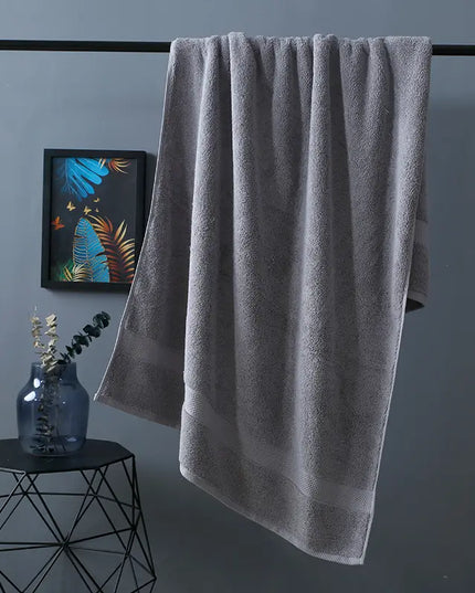 Gray towel hanging on a rack with a decorative plant and abstract art in the background.
