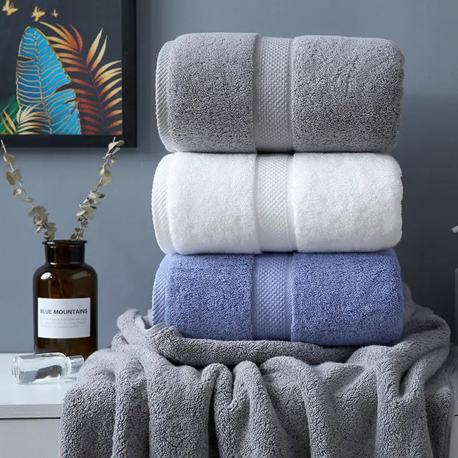 Stack of gray, white, and blue towels with a bottle and decorative elements in the background.