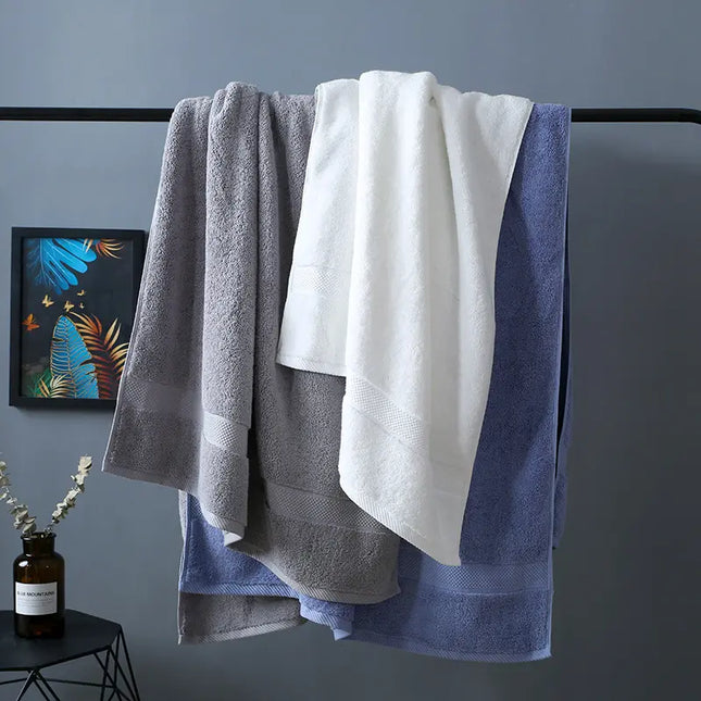 Three towels in gray, white, and blue hanging on a rack against a gray wall.