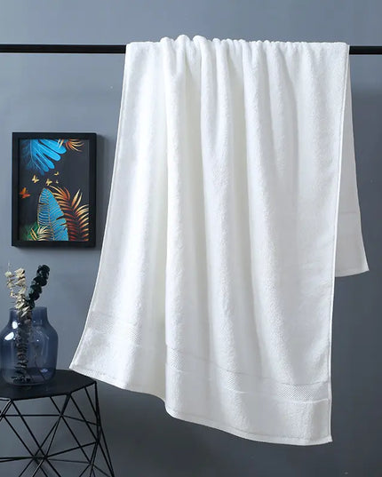 White towel hanging on a rack against a gray wall with a decorative plant and vase on a small table.