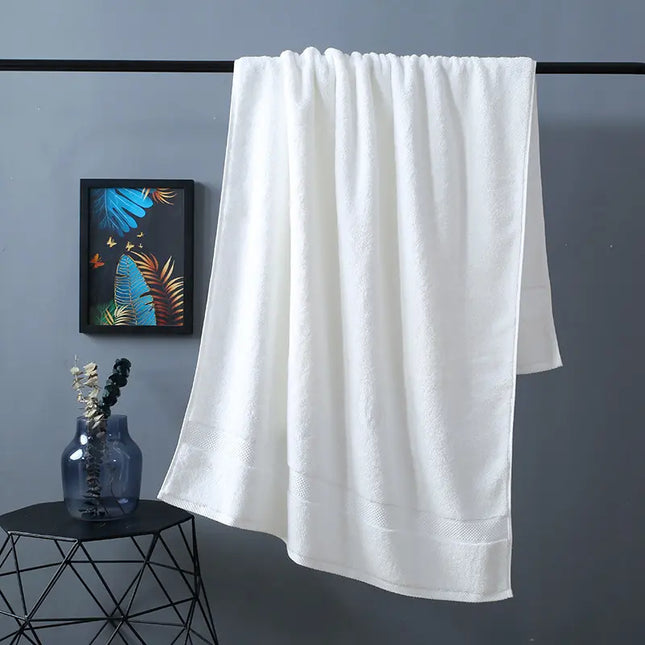 White towel hanging on a rack against a gray wall with a decorative plant and vase on a small table.