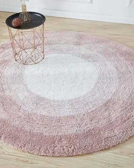 Round pink rug on a wooden floor with a small table.