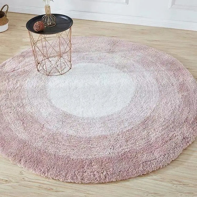 Round pink rug on a wooden floor with a small table.