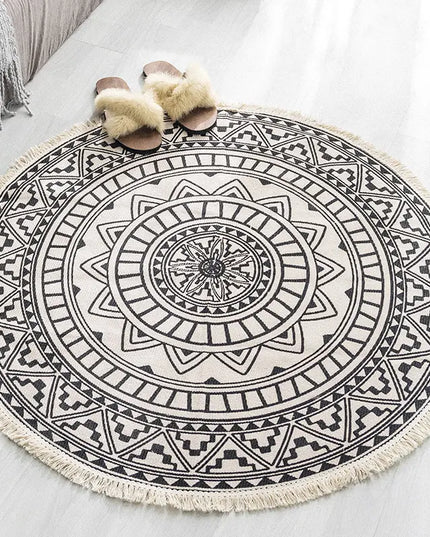 Round black and white patterned rug with tassels on a light surface.