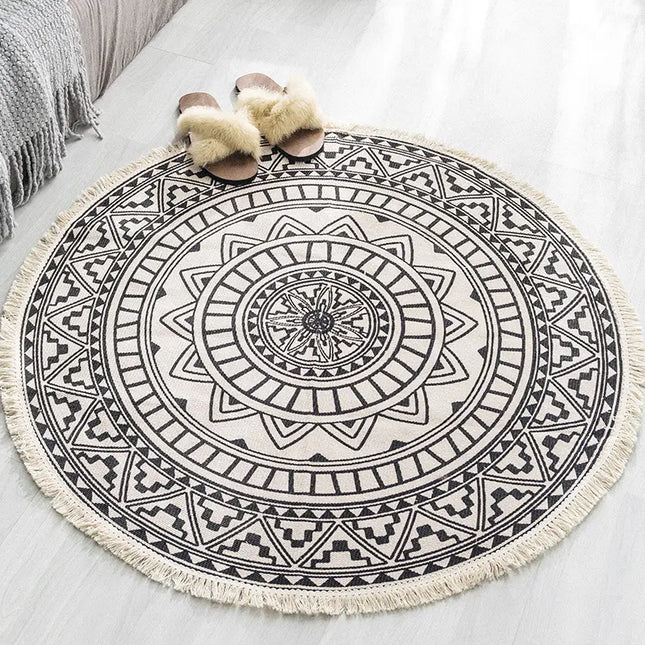 Round black and white patterned rug with tassels on a light surface.