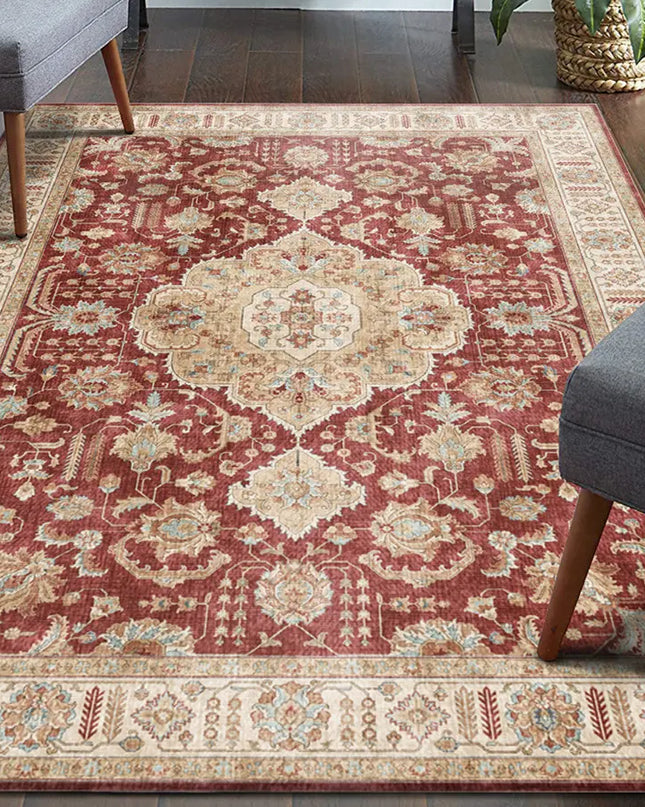 Decorative red and beige patterned rug in a living room setting with gray chairs.