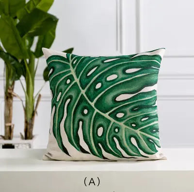 Decorative pillow with green leaf pattern on a white surface