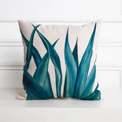 Decorative pillow with teal leaf pattern on a white background