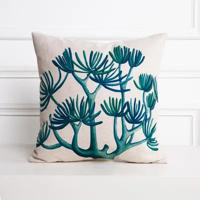 Decorative pillow with teal plant pattern on a white background