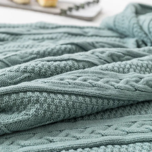 Close-up of a textured green blanket with cable knit pattern