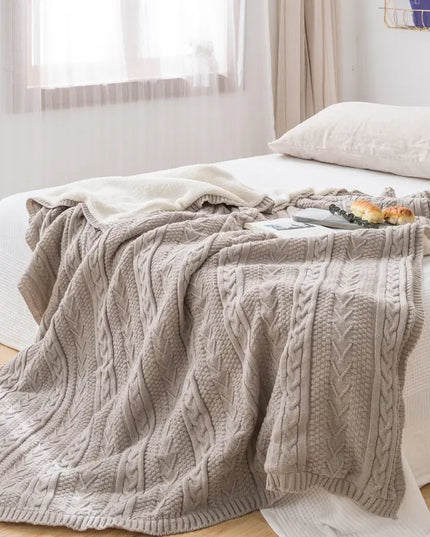 Gray cable knit blanket on a bed in a bright bedroom