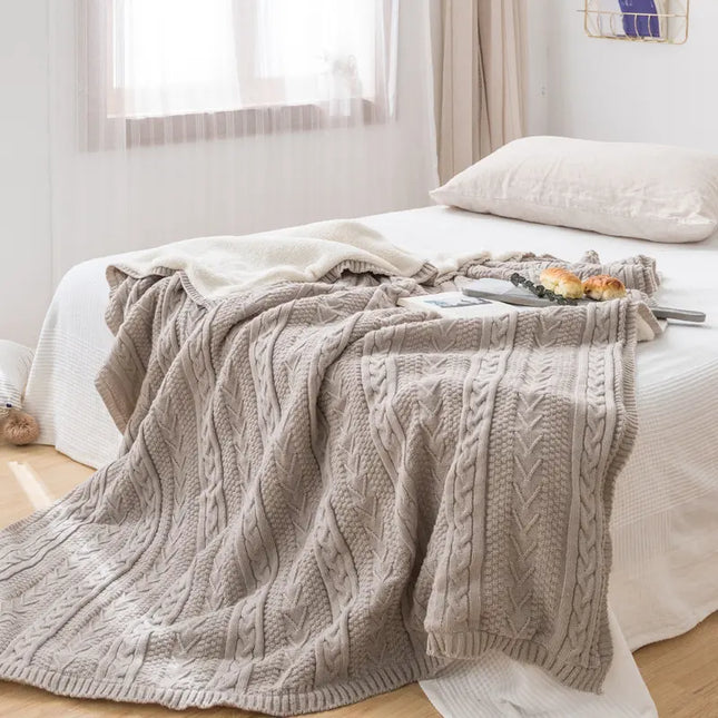 Gray cable knit blanket on a bed in a bright bedroom