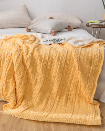 Yellow knitted blanket on a bed in a bedroom setting