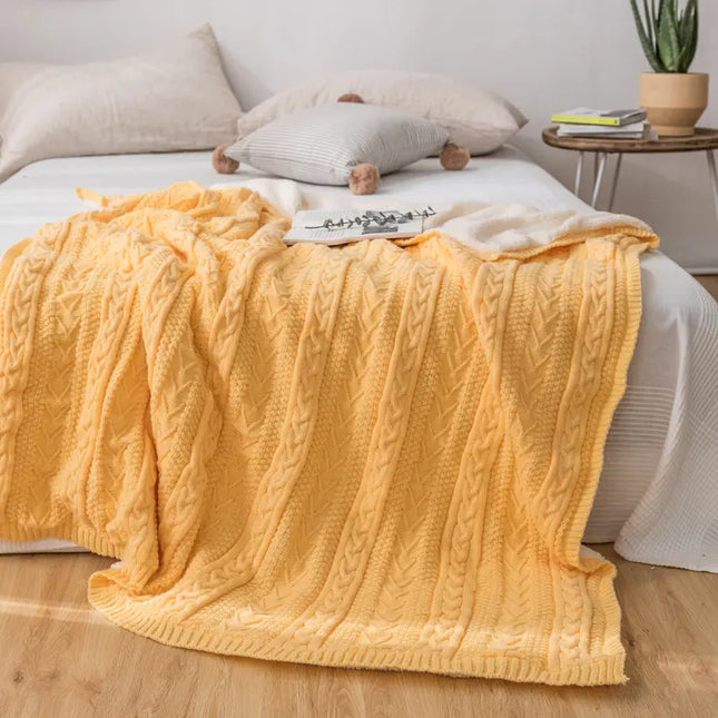 Yellow knitted blanket on a bed in a bedroom setting