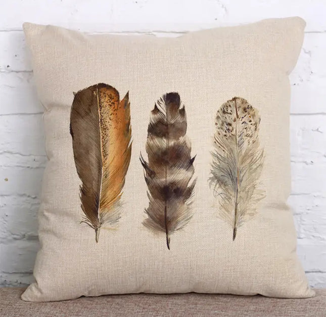 Decorative pillow with three feather illustrations on a textured surface.